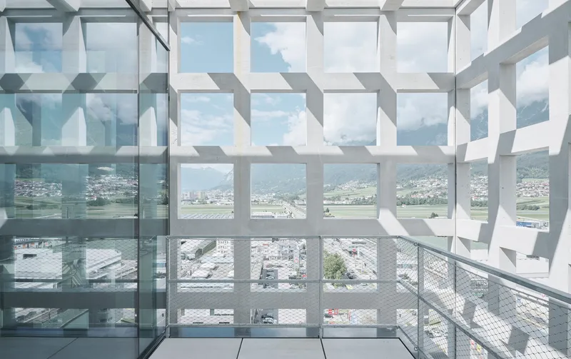 Geometric white sun screen casting patterned shadows across a glass-floored balcony with valley views