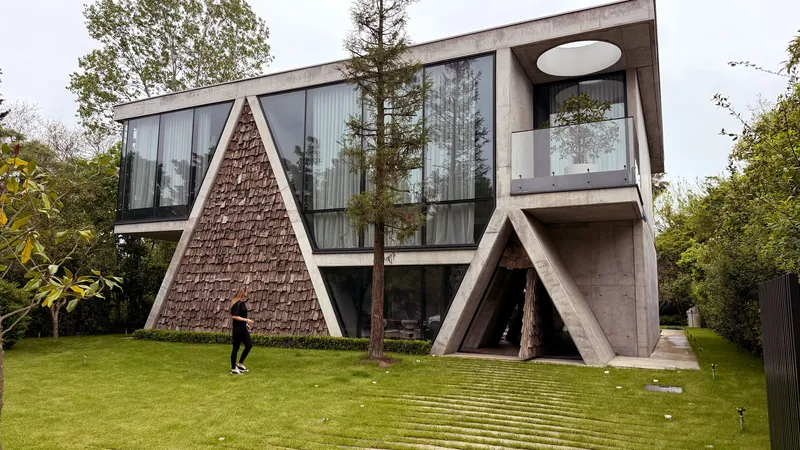 Side view of the triangular textured volume and diagonal concrete supports with a person walking on lawn
