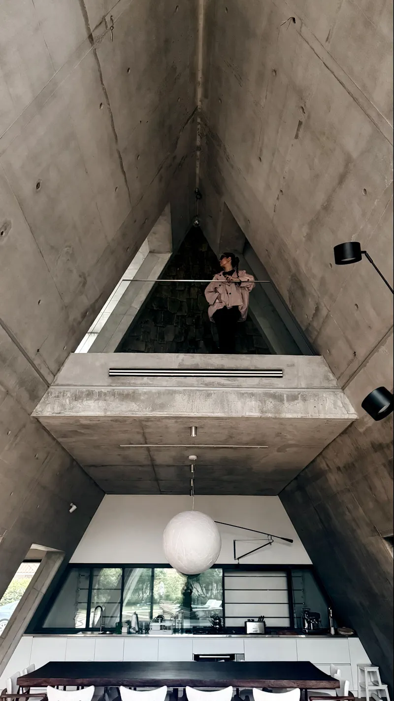 Upward view of the double-height concrete volume with a person standing on the upper mezzanine level