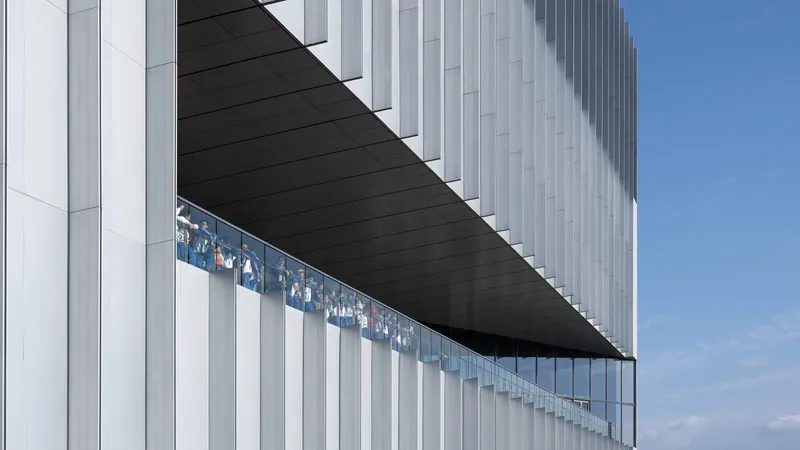 Exterior cantilever with vertical white metal fins and black soffit under blue sky