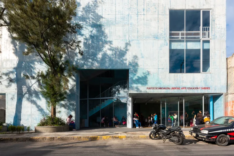 Street facade with board-marked concrete walls and large rectangular window opening above a covered entrance