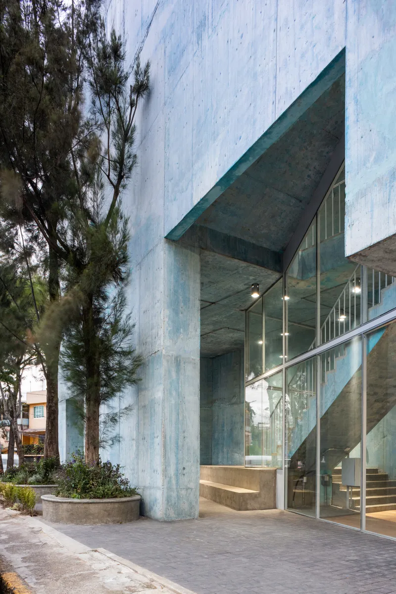 Ground-level view of the glass-enclosed stairwell with white metal railings and suspended pendant lights