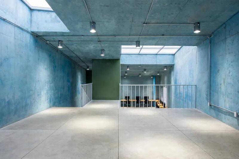 Upper level concrete floor with exposed ceiling, track lighting, and a rectangular skylight above the stair void