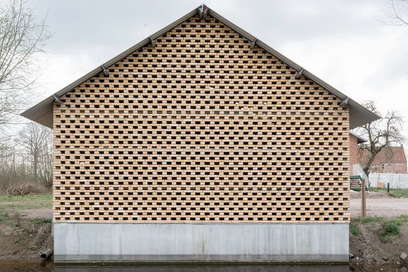 Gable end with chequered brick pattern atop a concrete plinth under an overcast sky
