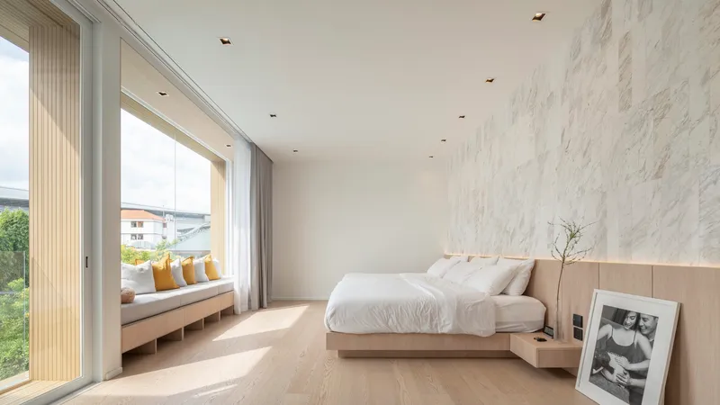 Bedroom with window seat, timber bed and marble wall panel illuminated by morning sunlight