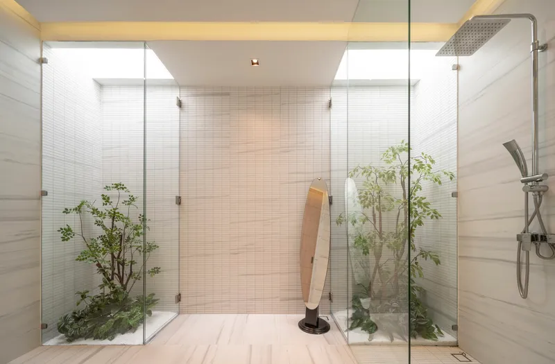 Bathroom with glass-enclosed planting beds flanking a timber bench and overhead rain shower