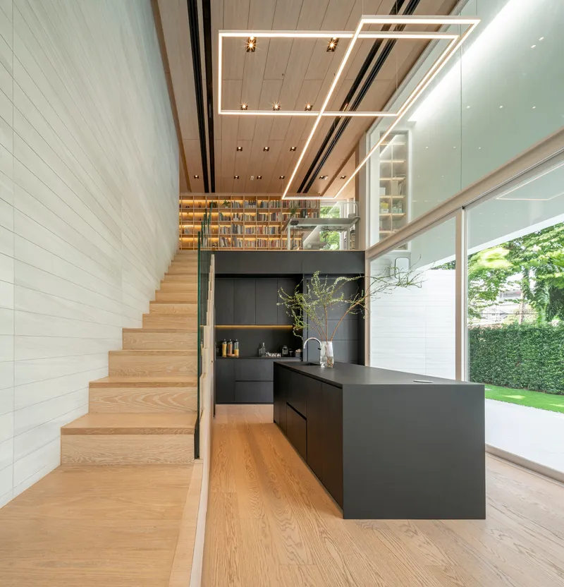 View of timber stair against white-tiled wall with rectangular ceiling light fixture above kitchen