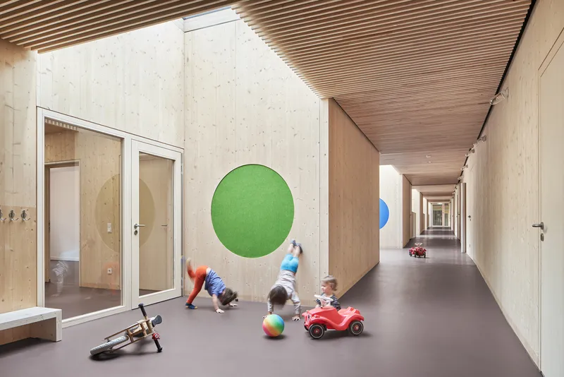 Corridor with slatted timber ceiling and children playing near circular green wall graphic