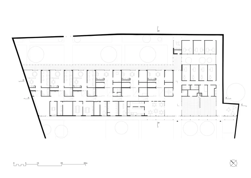 Floor plan drawing showing repeated linear classroom units flanking a corridor with circular elements