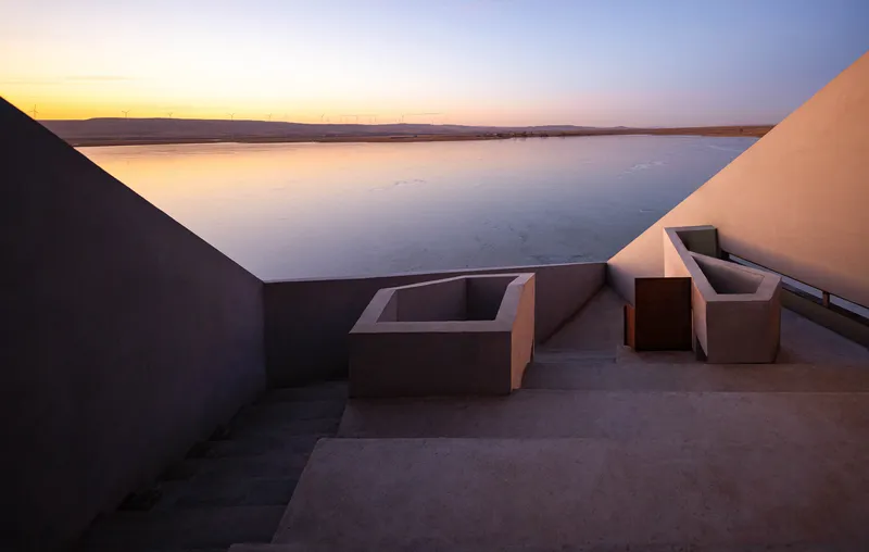Rooftop terrace with angular concrete seating and planters framing the lake view at twilight