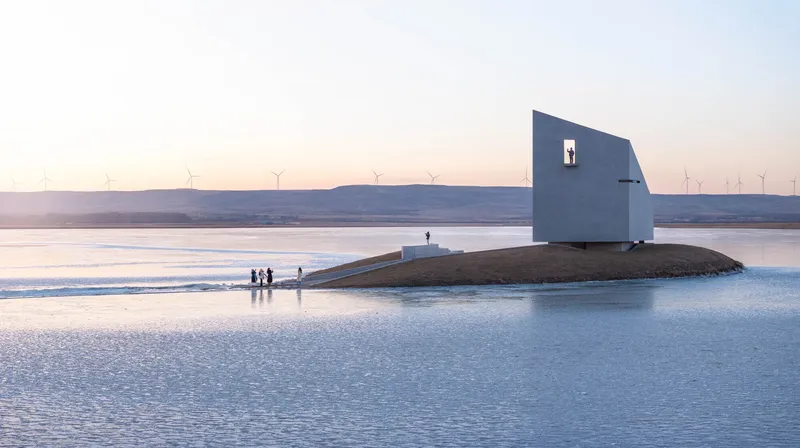 White cubic volume with square window on artificial mound surrounded by ice and visitors at dusk