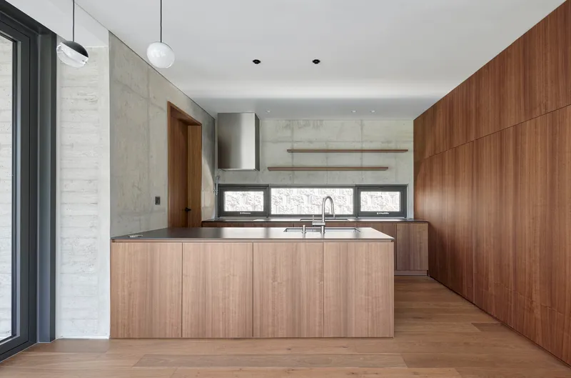 Open kitchen featuring timber cabinetry, stainless steel range hood and horizontal window band below concrete backsplash