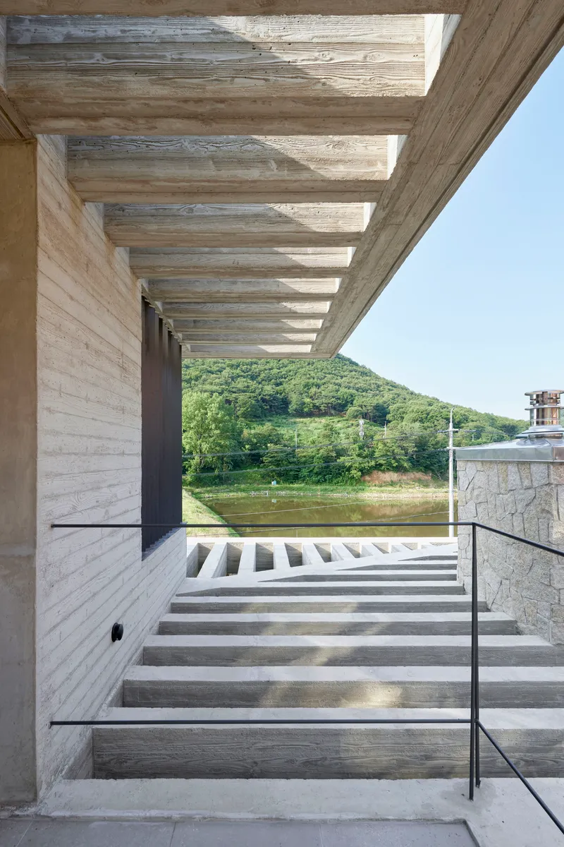 Covered concrete staircase descending toward a river with green hills in the background
