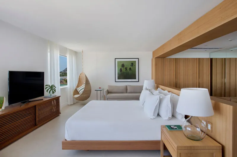 Bedroom with timber headboard beam and a suspended wicker chair beside the platform bed