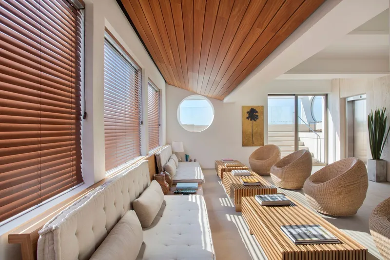 Slatted wood ceiling above a living area with venetian blinds filtering afternoon sunlight