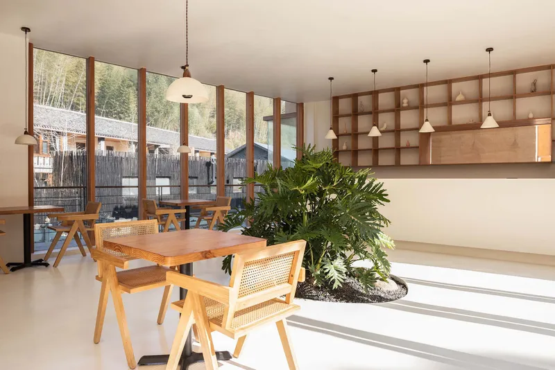 Interior dining area with gridded timber shelving, pendant lights, and a planted bed beneath windows