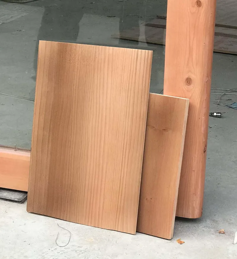 Wood panel samples and timber sections resting on a concrete floor