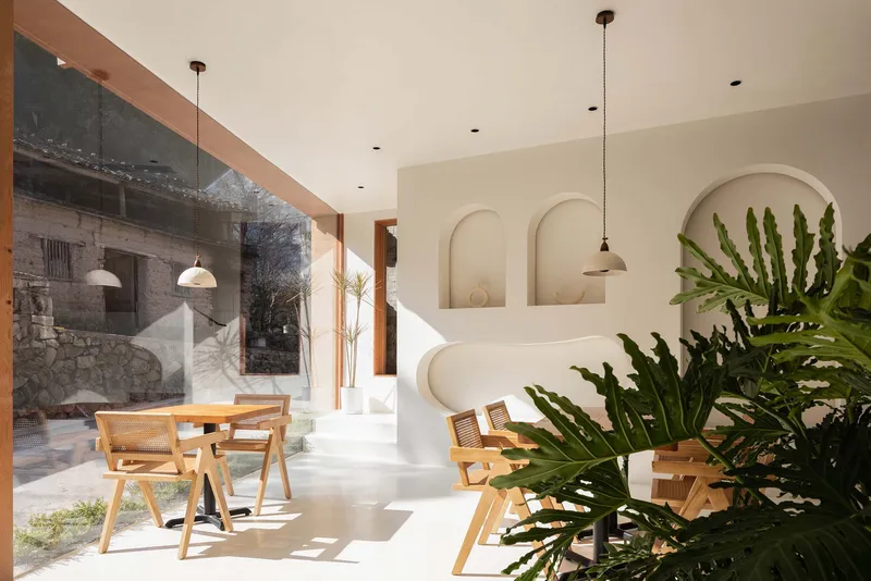 White-plastered alcoves with arched niches beside a dining area with potted plants