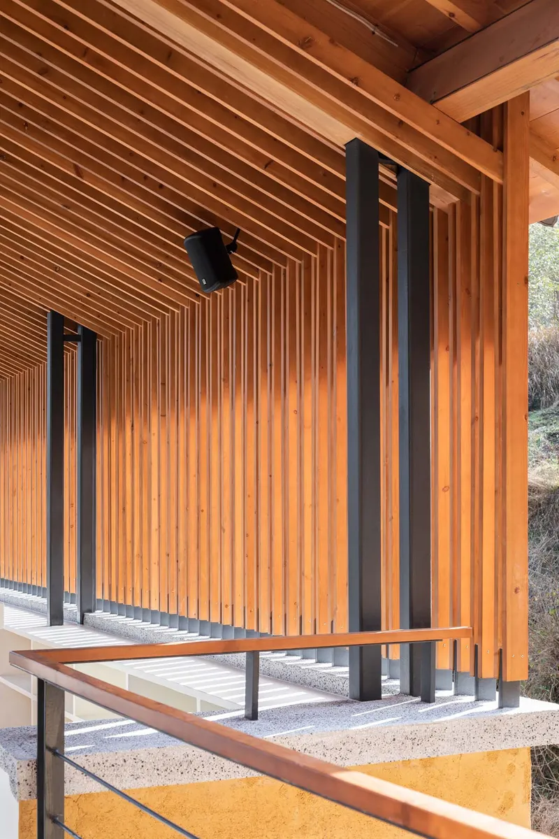 Covered porch with vertical timber slat wall and ceiling supported by slender black steel columns