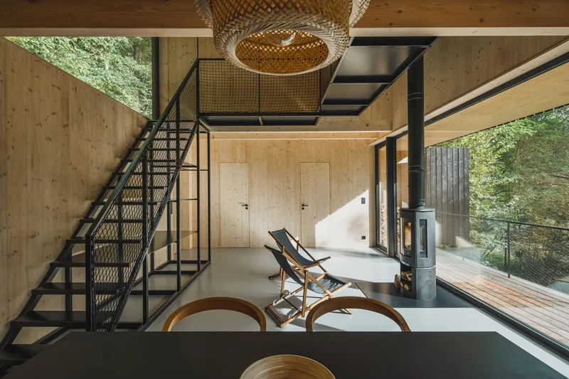 Living area with mesh-infill staircase, wicker light fixture, and glazed opening to timber deck