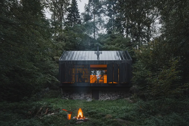 Rear facade with standing seam metal roof and glazed opening above a campfire