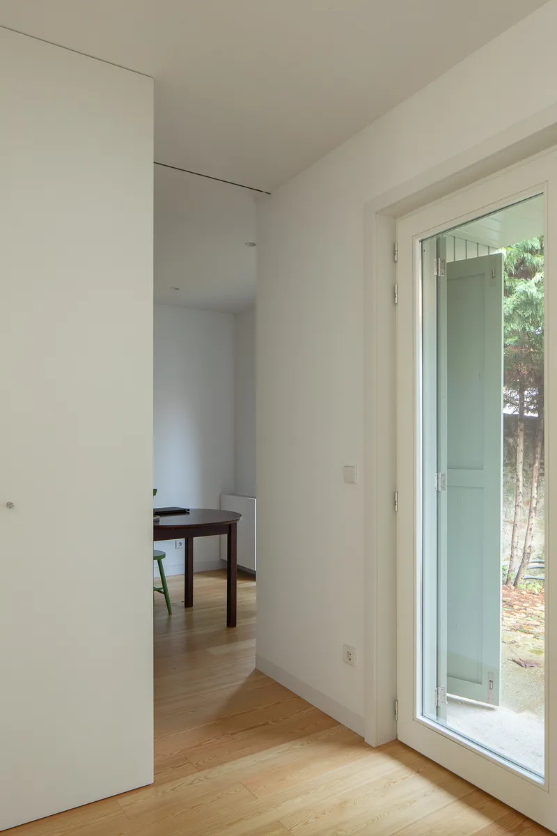 Circulation space with full-height glazed door opening to a garden with pine needles underfoot