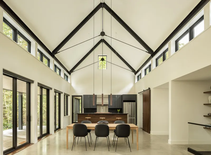 Vaulted ceiling with black steel trusses over dining area and polished concrete floor
