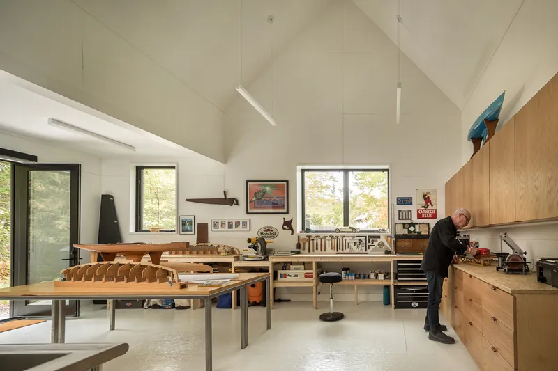 Workshop space with timber workbenches and boat-building project under vaulted ceiling with clerestory windows