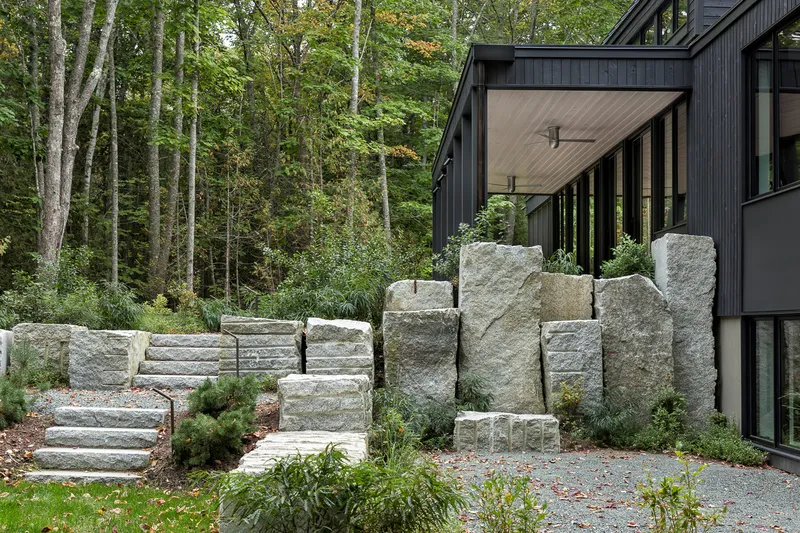 Stacked granite blocks forming a retaining wall with integrated stairs leading to the covered entry porch