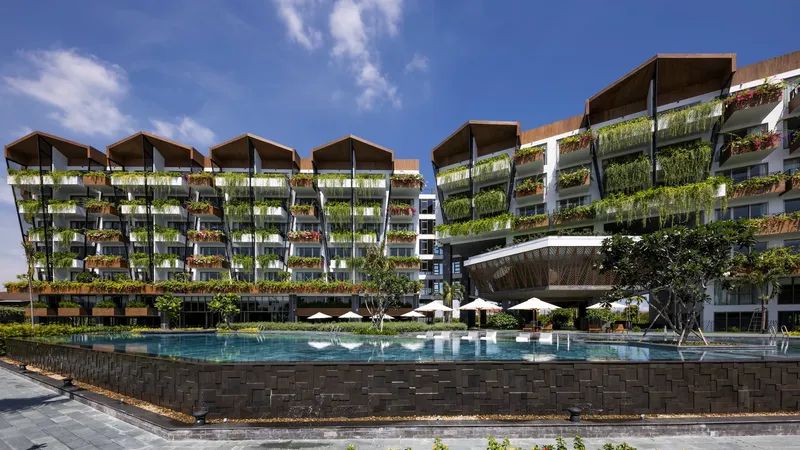 Pool deck with dark stone wall edging and planted facade rising behind white umbrellas and lounge chairs