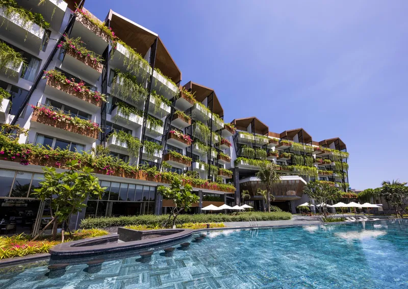 Stepped balconies planted with cascading greenery and flowering vines overlooking a tiled pool deck