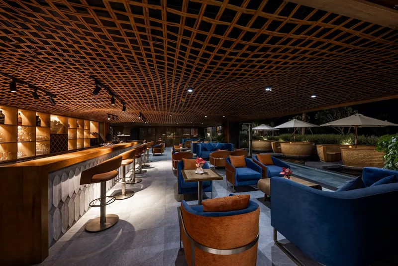 Bar and lounge area with diamond-pattern timber lattice ceiling and outdoor terrace at night