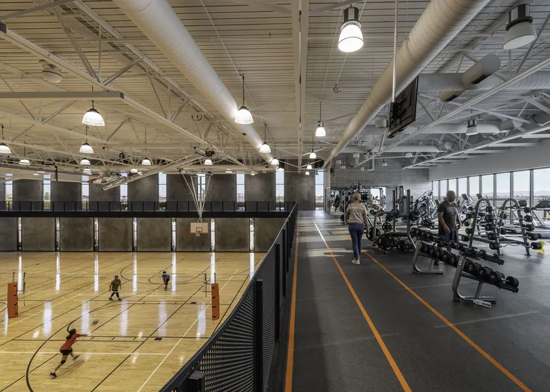 Basketball court alongside fitness area with exposed ductwork and wood slat ceiling