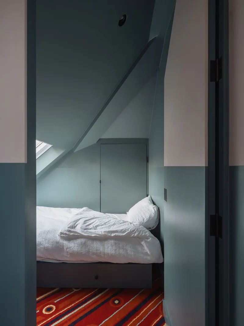 Doorway view into a small bedroom with sloped ceiling and skylight