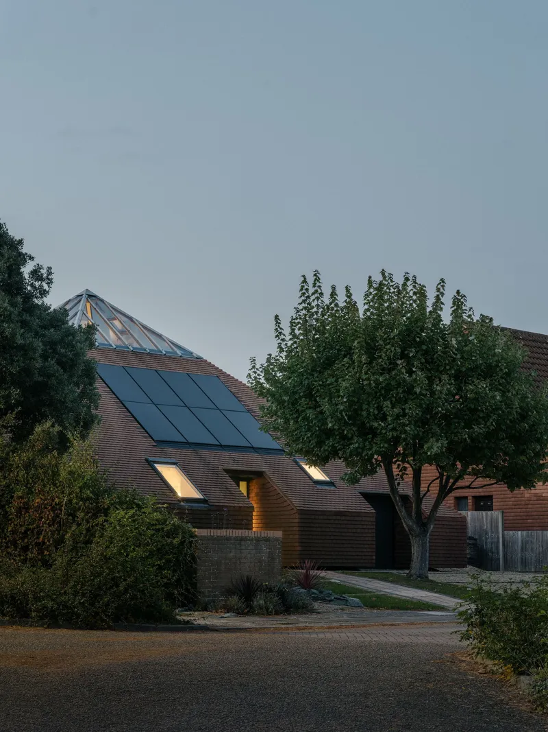 Street view of the tiled roof with integrated solar panels and skylight at dusk