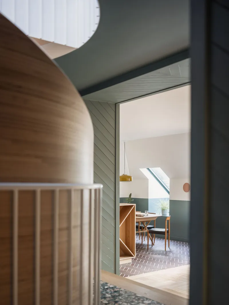 View through the hallway into the dining room with vertical timber paneling and skylight overhead
