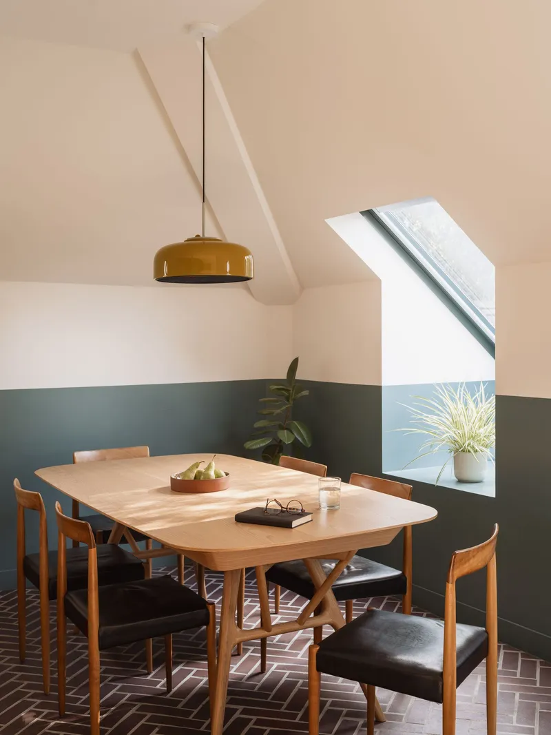 Dining room with brass pendant light and angled skylight illuminating the terrazzo tile floor