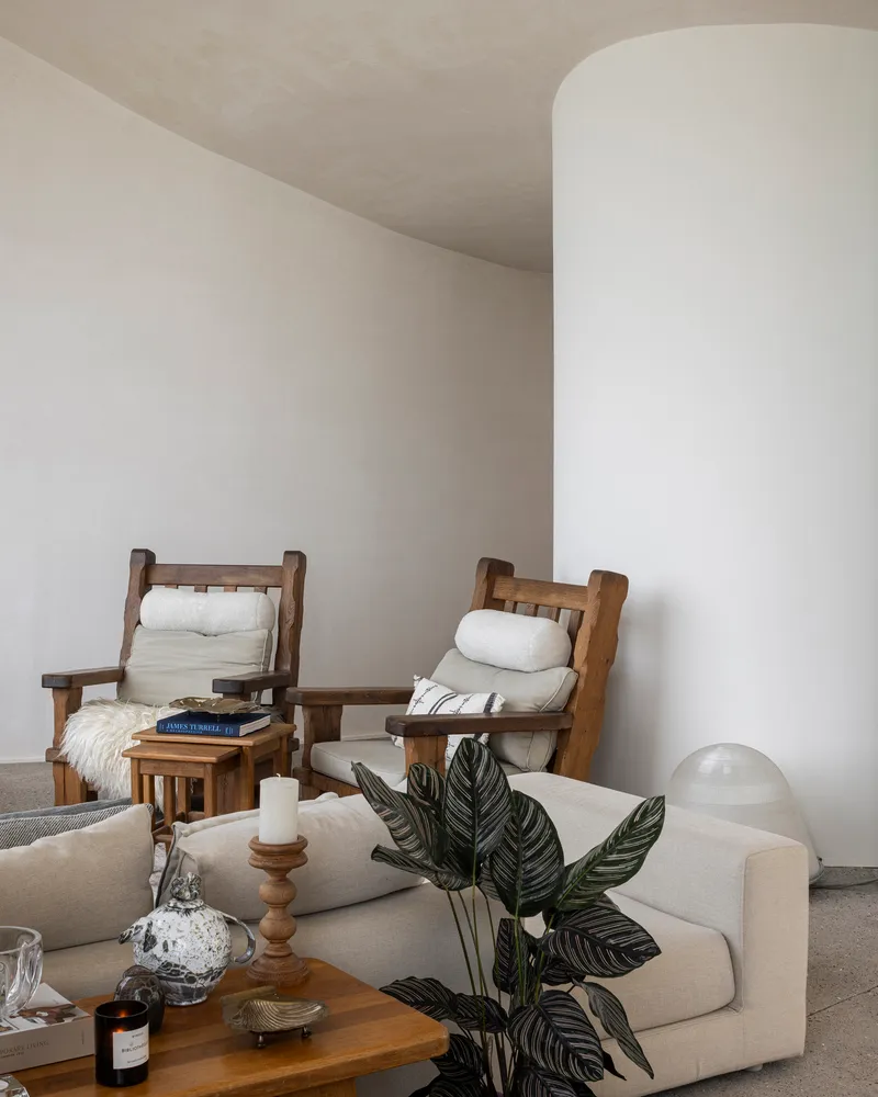 White cylindrical column beside seating area with indoor plant and arched ceiling above