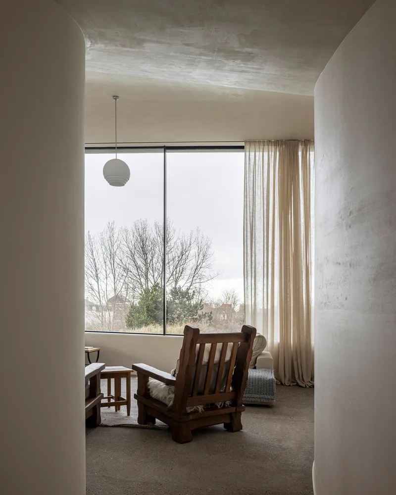Room framed by curved plaster walls with large window overlooking bare winter trees