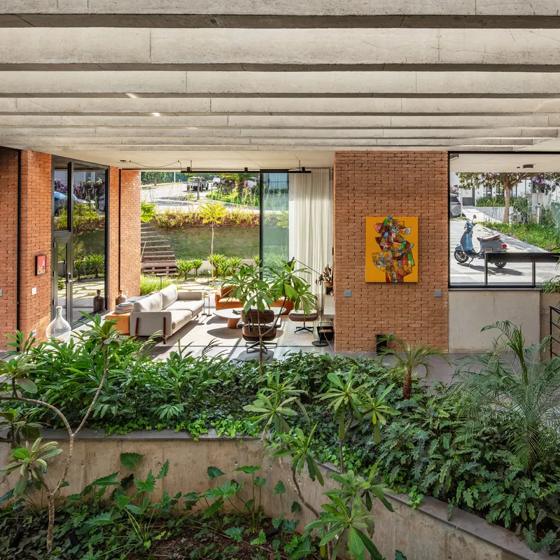 Multi-level interior courtyard with planted beds, exposed brick walls and concrete beam ceiling above living spaces