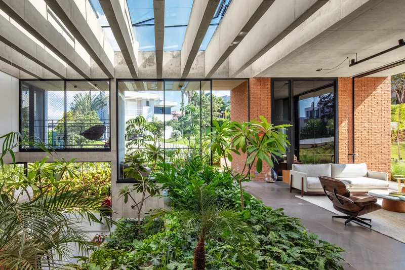 Interior planted courtyard with concrete beam roof and glazed perimeter walls under bright sun