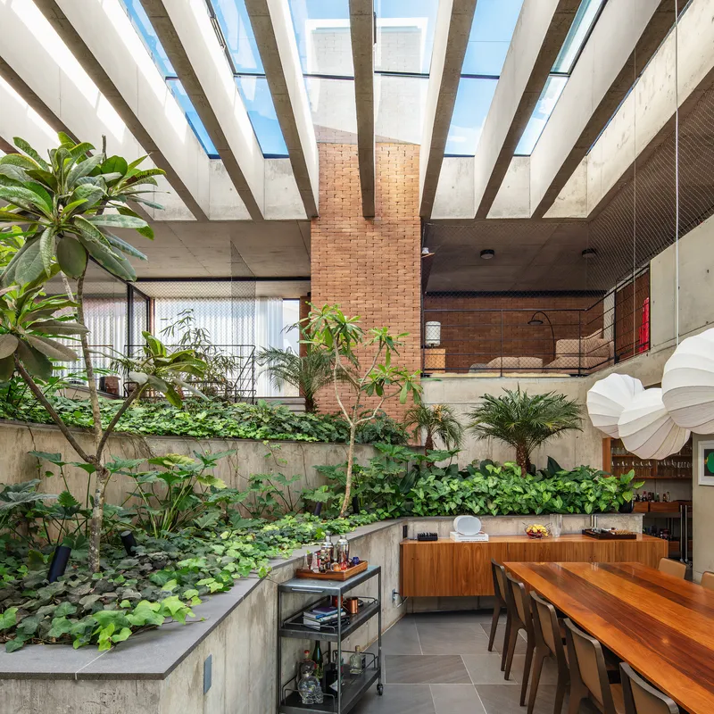 View across terraced planted beds toward upper mezzanine with timber cabinetry and hanging pendant lamp