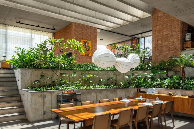 Dining zone with tiered concrete planters filled with greenery beneath exposed concrete ceiling beams