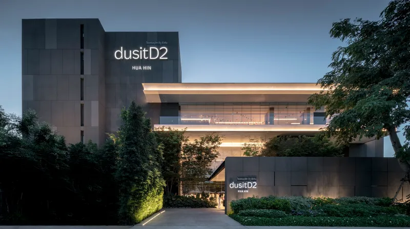 Entry drive approaching the cantilevered horizontal volume with dark vertical tower behind