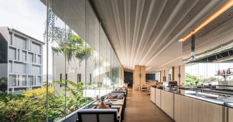 Glazed dining hall with radial ceiling fins overlooking landscaped courtyard beyond