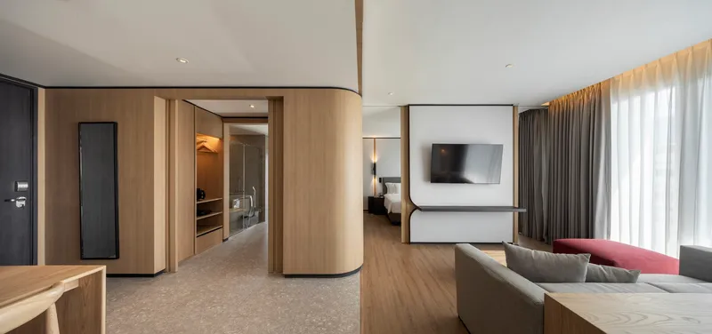Suite interior with curved timber veneer walls dividing the sleeping area from the living space