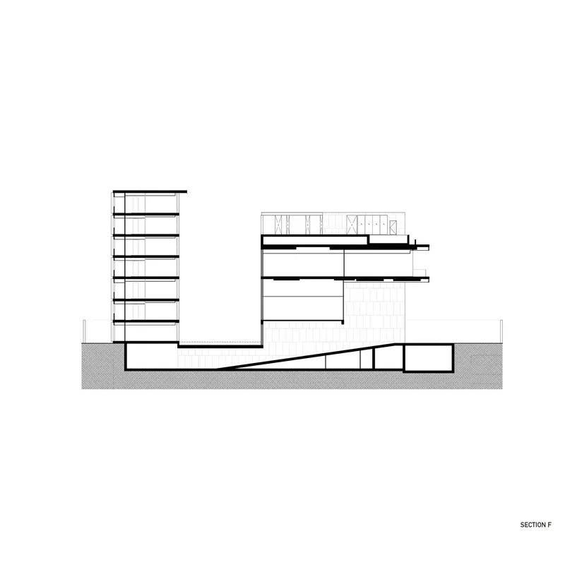 Section drawing revealing the sloped floor of the auditorium beneath the tower and horizontal wing