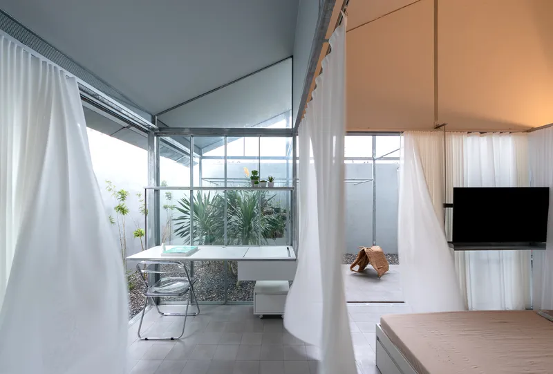 Dining nook adjacent to a planted courtyard with white walls and clerestory glazing