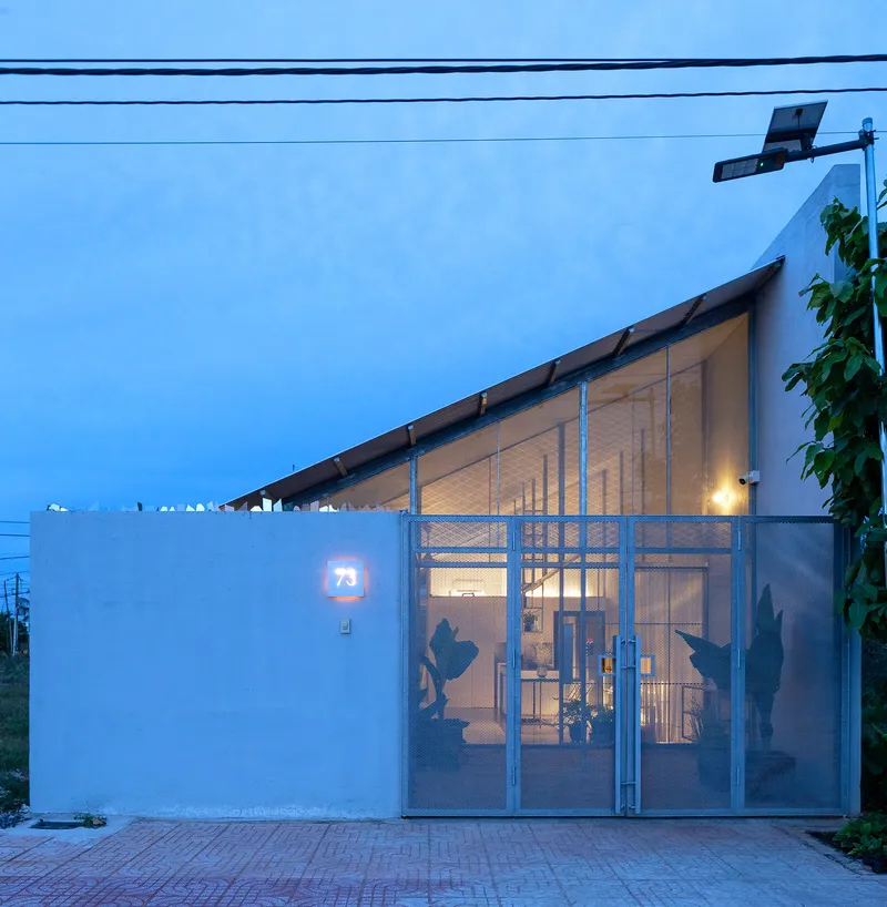 Street facade with sliding metal gate and pitched timber roof at dusk
