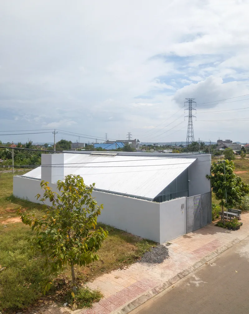 Gabled metal roof volume rising above grey masonry walls in a suburban lot with power lines overhead